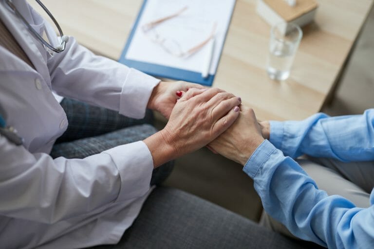 Caring Female Doctor Holding Hands with Patient Closeup