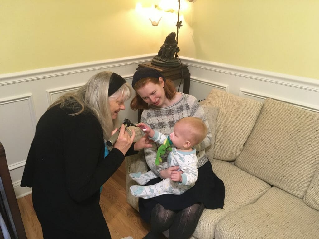 women on couch with baby while dr conaway gives baby checkup